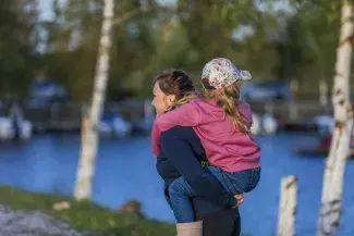 Lapsi aikuisen reppuselässä.