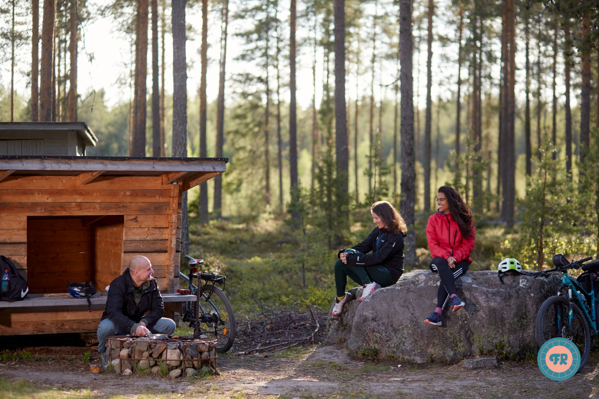 Cyclists sitting at a lean-to in the forest.